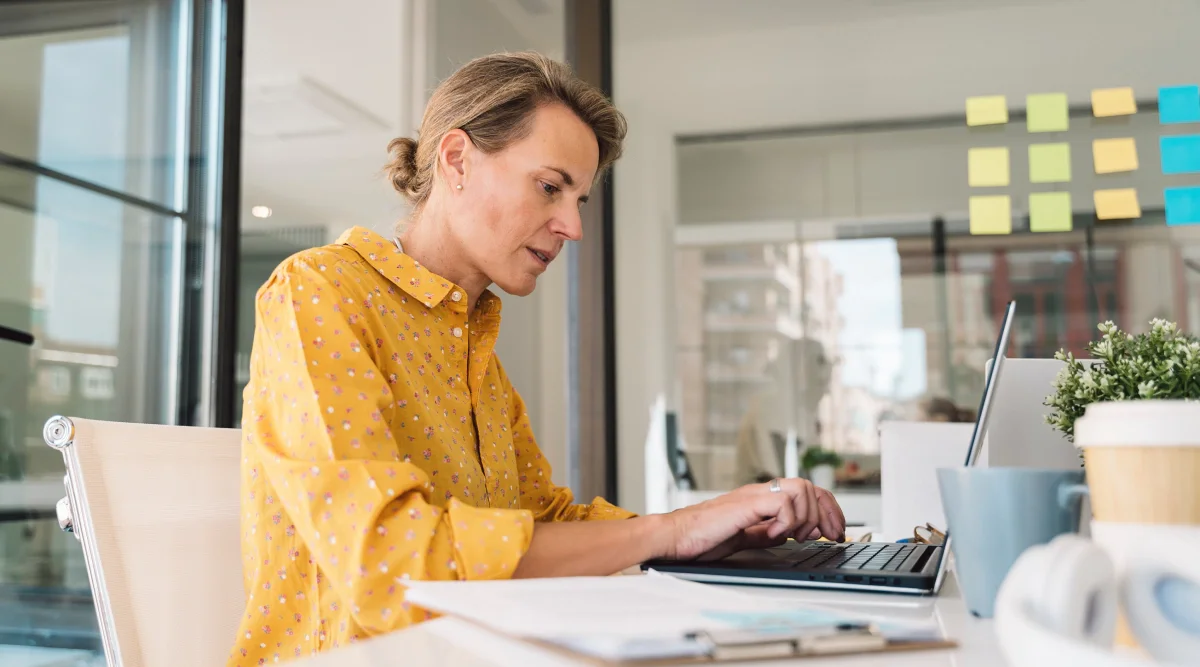 Woman in yellow shirt working on a laptop
