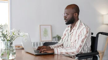 A man browses bank options for his nonprofit on his computer in a modern, well-lit apartment